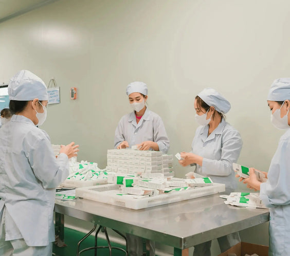 Factory workers packaging Atoskin Cream in a clean manufacturing facility to ensure product hygiene and safety for sensitive skin users.