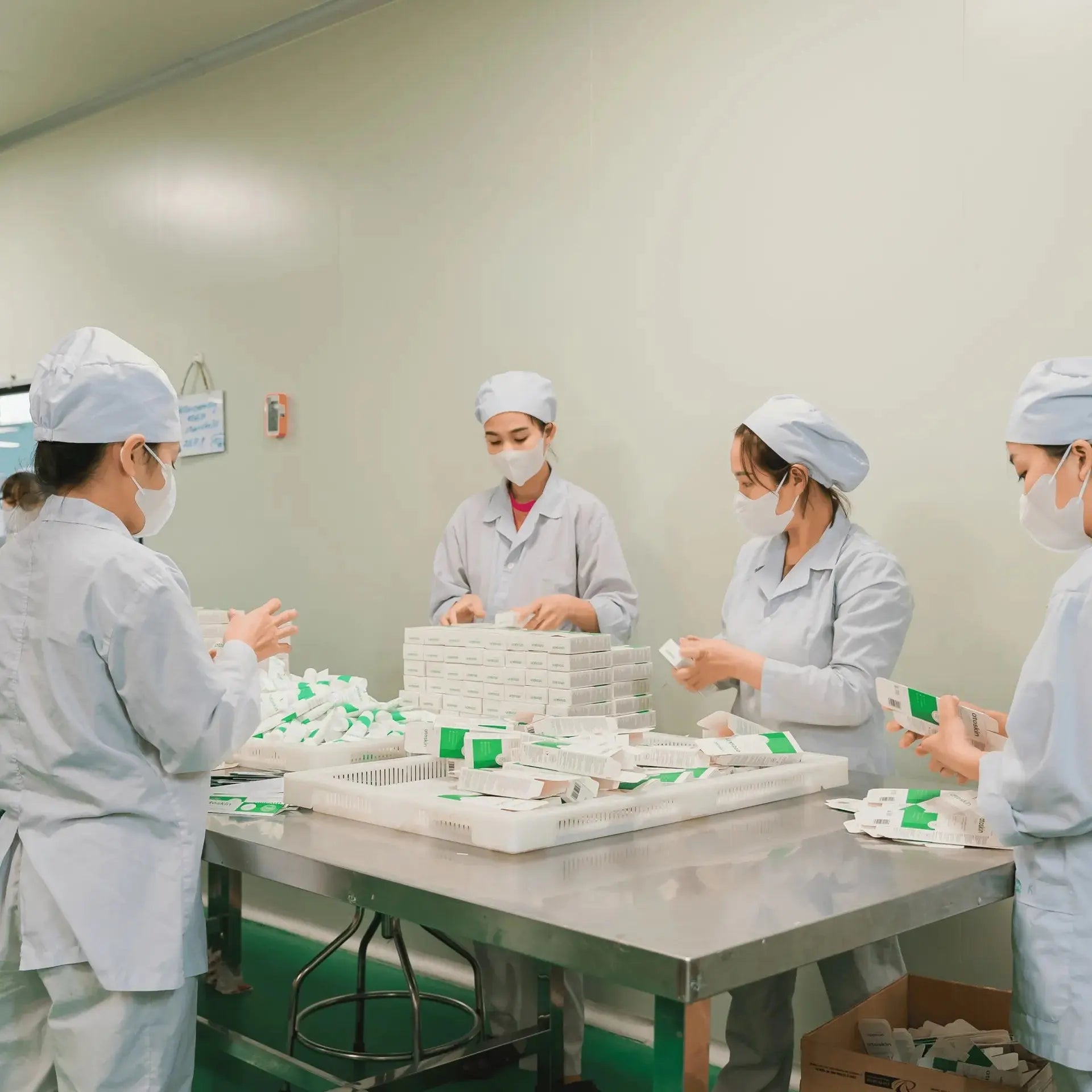Factory workers packaging Atoskin Cream in a clean manufacturing facility to ensure product hygiene and safety for sensitive skin users.