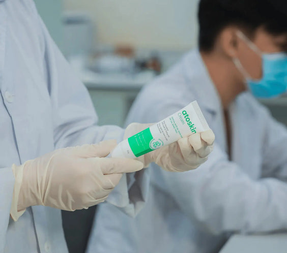 Lab technician inspecting Atoskin Cream tube during quality control testing to ensure product safety and effectiveness for eczema-prone skin.