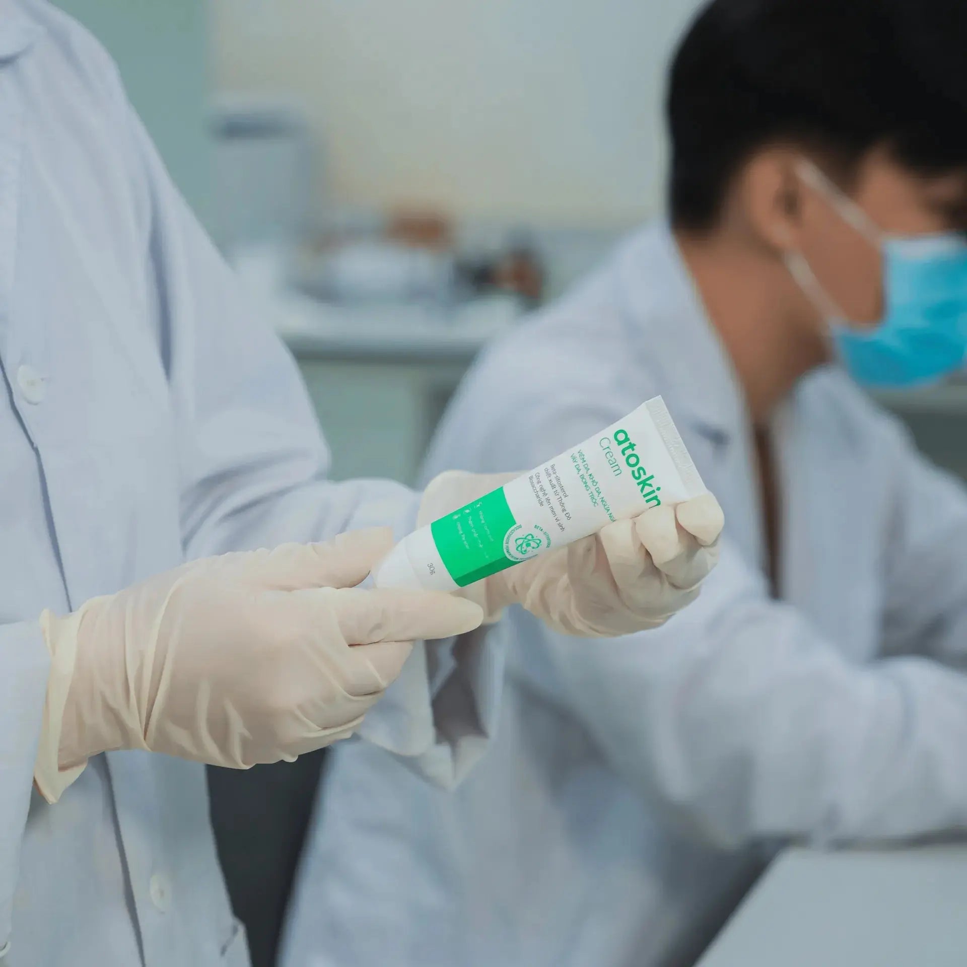 Lab technician inspecting Atoskin Cream tube during quality control testing to ensure product safety and effectiveness for eczema-prone skin.